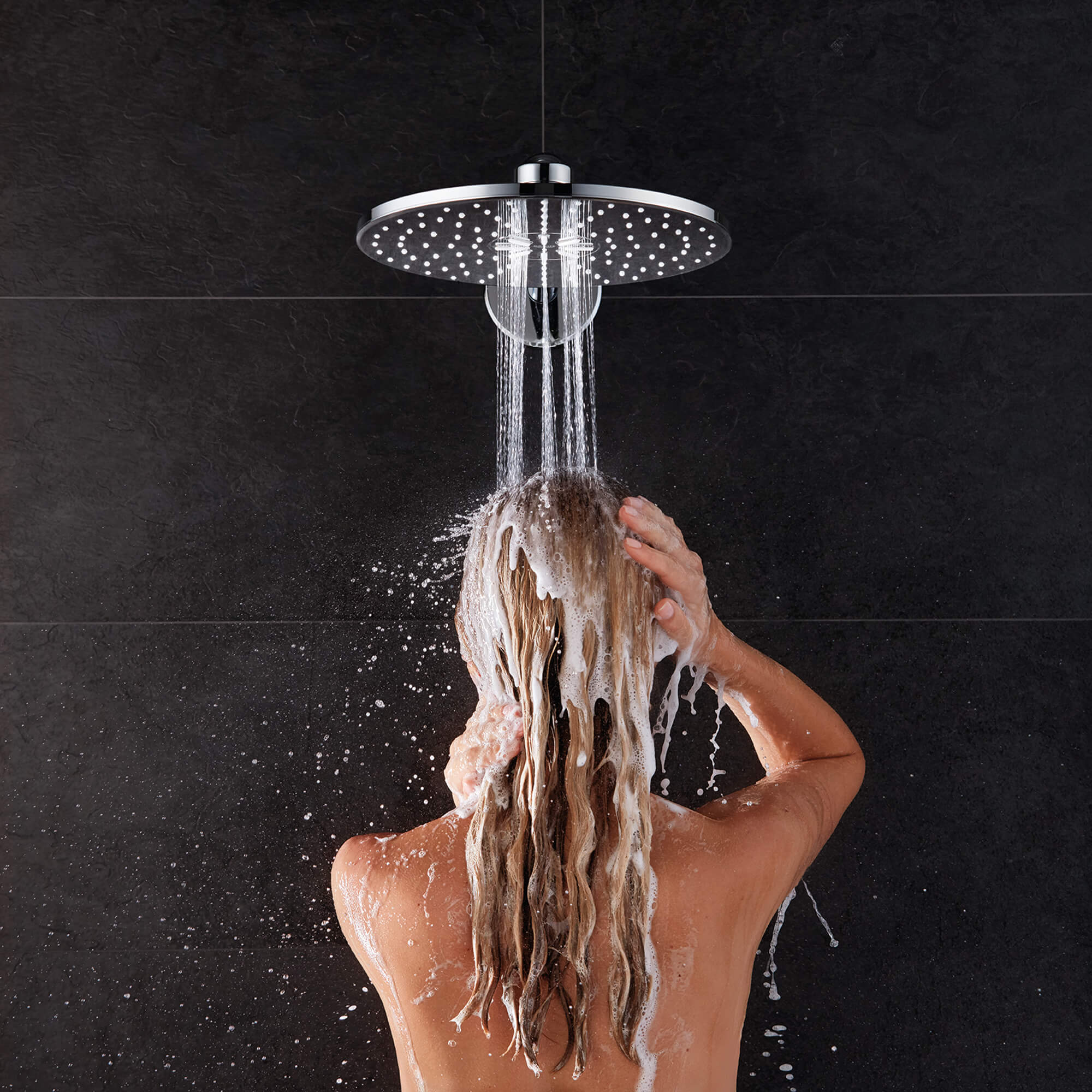 person showering under round rainshower showerhead